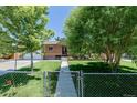Inviting front yard featuring lush trees, a vibrant green lawn, and a charming brick home at 9170 Aspen Dr, Thornton, CO 80229