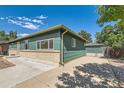Well-maintained home featuring a brick foundation, green siding, and a spacious driveway under a bright sky at 5556 Vaughn St, Denver, CO 80239