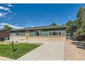 Inviting single-Gathering home featuring a manicured lawn, mature trees and a long concrete driveway at 5556 Vaughn St, Denver, CO 80239