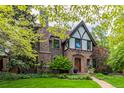 Charming stone Tudor home with a manicured front yard, a stone walkway leading to the front door, and lush landscaping at 1795 N Monaco St Pkwy, Denver, CO 80224