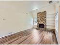 Spacious living room featuring a striking stone fireplace and wood-look floors at 13598 E Asbury Dr, Aurora, CO 80014