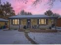 Brick ranch home with snowy yard, illuminated at dusk at 424 S Leyden St, Denver, CO 80224