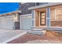 Inviting front entrance with stone accents, steps leading up to a black modern door and a two-car garage at 2957 Eagle Wing Way, Castle Rock, CO 80109