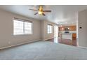 Open-concept living room with large windows, ceiling fan, and seamless transition to the kitchen at 2965 Deerfoot Way, Castle Rock, CO 80109