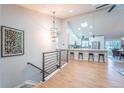 Inviting open-concept with light-wood floors, counter seating, and a modern chandelier over the stairwell at 1248 Ilium Dr, Lafayette, CO 80026
