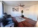 Inviting living room featuring hardwood floors, a ceiling fan, and a comfortable, oversized couch at 5411 Chandler Way, Denver, CO 80239