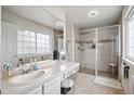 Bright bathroom with vanity, large mirror, tiled shower with glass door, and abundant lighting at 13228 E Asbury Dr, Aurora, CO 80014