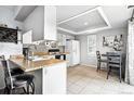 Efficient kitchen with white cabinetry, a breakfast bar, and dining area with tile floor at 13228 E Asbury Dr, Aurora, CO 80014