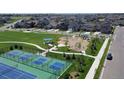 Aerial view of the community park featuring a playground, pickleball courts, and green spaces at 4689 Thistle Dr, Brighton, CO 80601