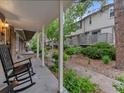 Covered front porch with cozy seating and view to landscaped green spaces at 7049 E Briarwood Cir, Centennial, CO 80112