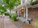 Inviting front porch with rocking chairs, brick detail and unit number above door at 7049 E Briarwood Cir, Centennial, CO 80112