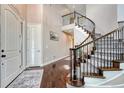 Elegant foyer with hardwood floors, white door, and an impressive curved staircase with decorative railings at 27625 E Moraine Dr, Aurora, CO 80016