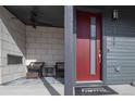 Welcoming front porch with seating area, modern red front door, and stylish exterior lighting at 10177 E 62Nd Ave, Denver, CO 80238