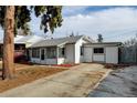 White ranch home with a spacious driveway and mature trees at 1256 Ulster St, Denver, CO 80220