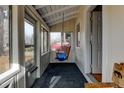Enclosed porch featuring large windows and a cozy swing, perfect for enjoying the outdoors in comfort at 1256 Ulster St, Denver, CO 80220