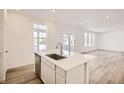 Open concept kitchen with island, stainless steel sink, and white cabinets at 5581 Wisteria Ave, Firestone, CO 80504