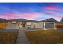 Charming home at dusk featuring a well-maintained yard, painted brick, and a gray two-car garage at 2341 Poze Blvd, Thornton, CO 80229