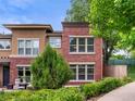 Exterior view of two-story townhome featuring red brick and stucco, with lush greenery at 8983 E Nichols Pl, Centennial, CO 80112