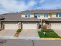 Charming townhome featuring a two-car garage, stone accents, well-maintained lawn, and inviting curb appeal at 3000 E 112Th Ave # 102, Northglenn, CO 80233