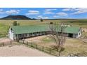 Aerial view of horse barn with a green roof and surrounding pastures at 6145 S Perry Park Rd, Sedalia, CO 80135