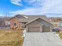 Charming home featuring stone accents, a three-car garage, and a manicured front yard at 10145 Deerfield St, Firestone, CO 80504