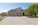 An eye-level exterior shot of the home showing the brickwork and the three-car garage at 10044 E 146Th Pl, Brighton, CO 80602