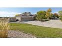 A well-manicured lawn with a charming outbuilding accompanies this home with a three-car garage at 10044 E 146Th Pl, Brighton, CO 80602