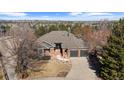 Aerial view of brick home with a two-car garage surrounded by a neighborhood with mountain views at 283 Huntley Ct, Castle Pines, CO 80108