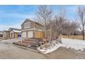 Two-story home features a two-car garage, brick accents, and landscaped front yard at 8799 Independence Way, Arvada, CO 80005