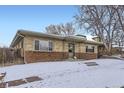 Inviting single-story brick home with a cozy entrance and snow-covered front yard at 3420 Tennyson St # 105, Denver, CO 80212