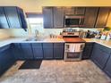 Well-lit kitchen features stainless steel appliances, dark cabinetry, and a practical double sink at 2874 Rose Hill St, Strasburg, CO 80136