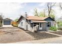 Gray bungalow with detached garage and driveway leading to backyard and quaint front porch at 4209 S Bannock St, Englewood, CO 80110