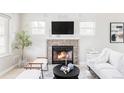 Bright living room with stone fireplace, large TV, and modern, neutral-toned furniture at 4209 S Bannock St, Englewood, CO 80110