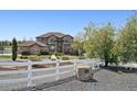 Sprawling home exterior featuring a white fence and mature trees, offering privacy at 14953 Akron Ct, Brighton, CO 80602