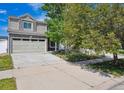 Two-story house featuring stone facade, attached garage, mature trees, and a well-maintained lawn at 4435 Andes Ct, Denver, CO 80249