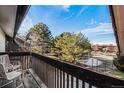 Relaxing balcony featuring wood deck, outdoor seating, and views of mature trees and tennis court at 14704 E 2Nd Ave # E307, Aurora, CO 80011