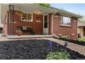 Charming brick home with a cozy front porch features a hanging flower basket and bench at 5185 N Meade Street St, Denver, CO 80221
