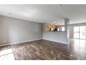 Open-concept living room with wood floors flowing into an eat-in kitchen area with bar-style counter at 1365 Waxwing Ave, Brighton, CO 80601