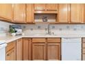 Close up of kitchen showing light wood cabinets, white appliances, and tile backsplash at 775 S Alton Way # 3C, Denver, CO 80247