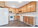 Well-lit kitchen featuring light wood cabinetry, white appliances, and a contrasting dark floor at 775 S Alton Way # 3C, Denver, CO 80247