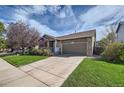 Exterior view showcasing the home's front facade, garage, driveway, and landscaped lawn at 11462 Iola St, Commerce City, CO 80640