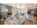 Open-concept living area with a cozy fireplace, wood floors, and seamlessly connected to the modern kitchen at 811 W 128Th Pl, Westminster, CO 80234