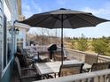 Outdoor deck area furnished with comfortable seating, dining table, and umbrella overlooking trees at 16135 Rock Crystal Dr, Parker, CO 80134