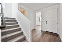 Bright foyer with wood floors, stairway, and white door, leading to other rooms in the house at 250 Lark Sparrow Way, Bennett, CO 80102