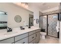 Modern bathroom featuring a double sink vanity, stylish mirrors, and a walk-in shower with decorative tile at 12301 Festival Ln, Thornton, CO 80241