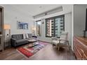 A well-lit living room showcases a comfortable sofa, modern chair, and colorful rug, complemented by city views at 1750 Wewatta St # 605, Denver, CO 80202