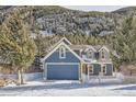 Two-story blue house with white fence, snowy yard and mountain backdrop at 1438 Marion St, Georgetown, CO 80444