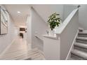 Bright hallway with light wood floors, stairs, and a decorative plant, creating a welcoming and modern entrance at 15595 E 47Th Dr, Denver, CO 80239