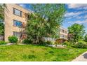 Exterior building view with green lawn, mature trees, and landscaping at 1450 Albion St # 204, Denver, CO 80220