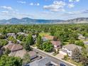 Aerial view of homes on tree-lined street, neighborhood park with tennis court, and picturesque mountain backdrop at 4059 Nevis St, Boulder, CO 80301